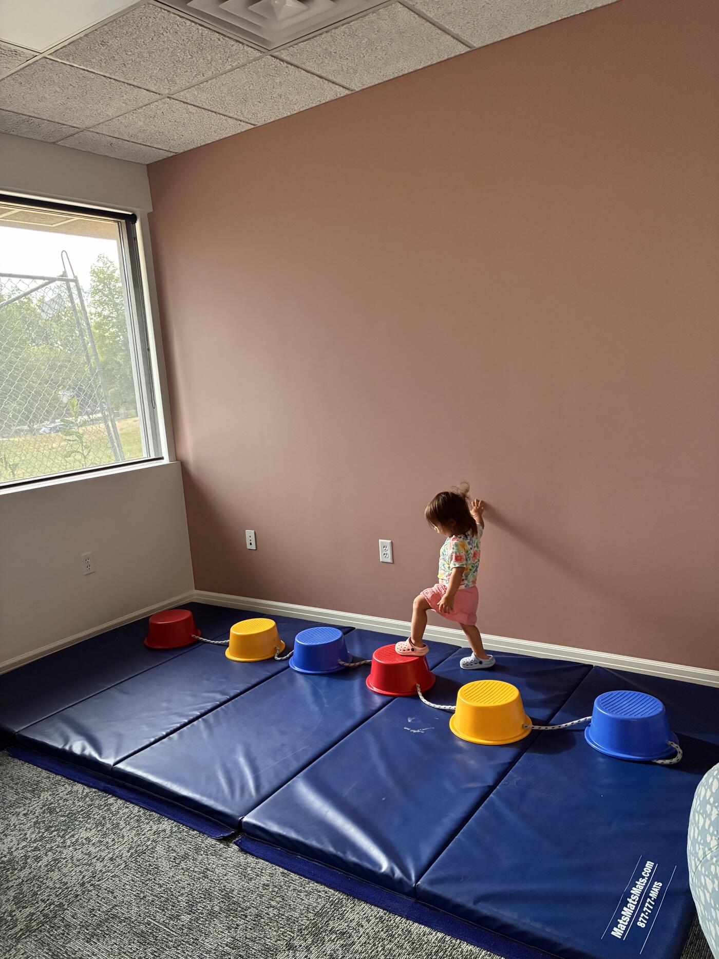 Child practicing balance and motor coordination on colorful stepping stones at SLOT clinic
